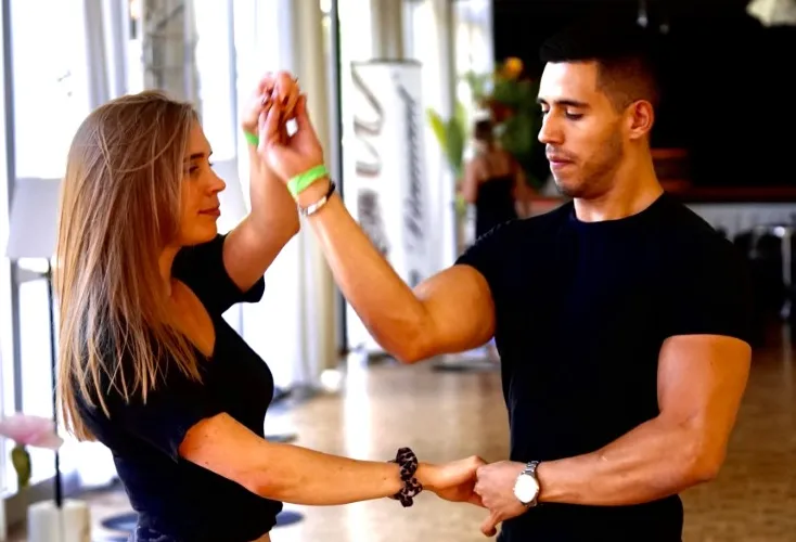 Bruno dancing Bachata at a congress, leading partner in a bright daytime space